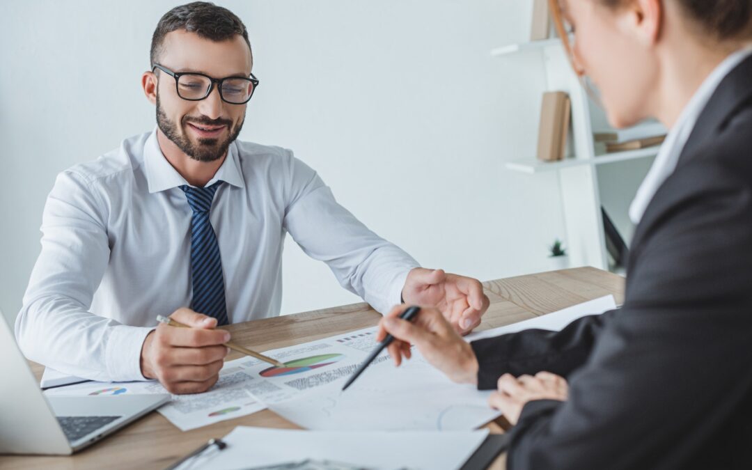 cheerful financiers pointing on documents in office
